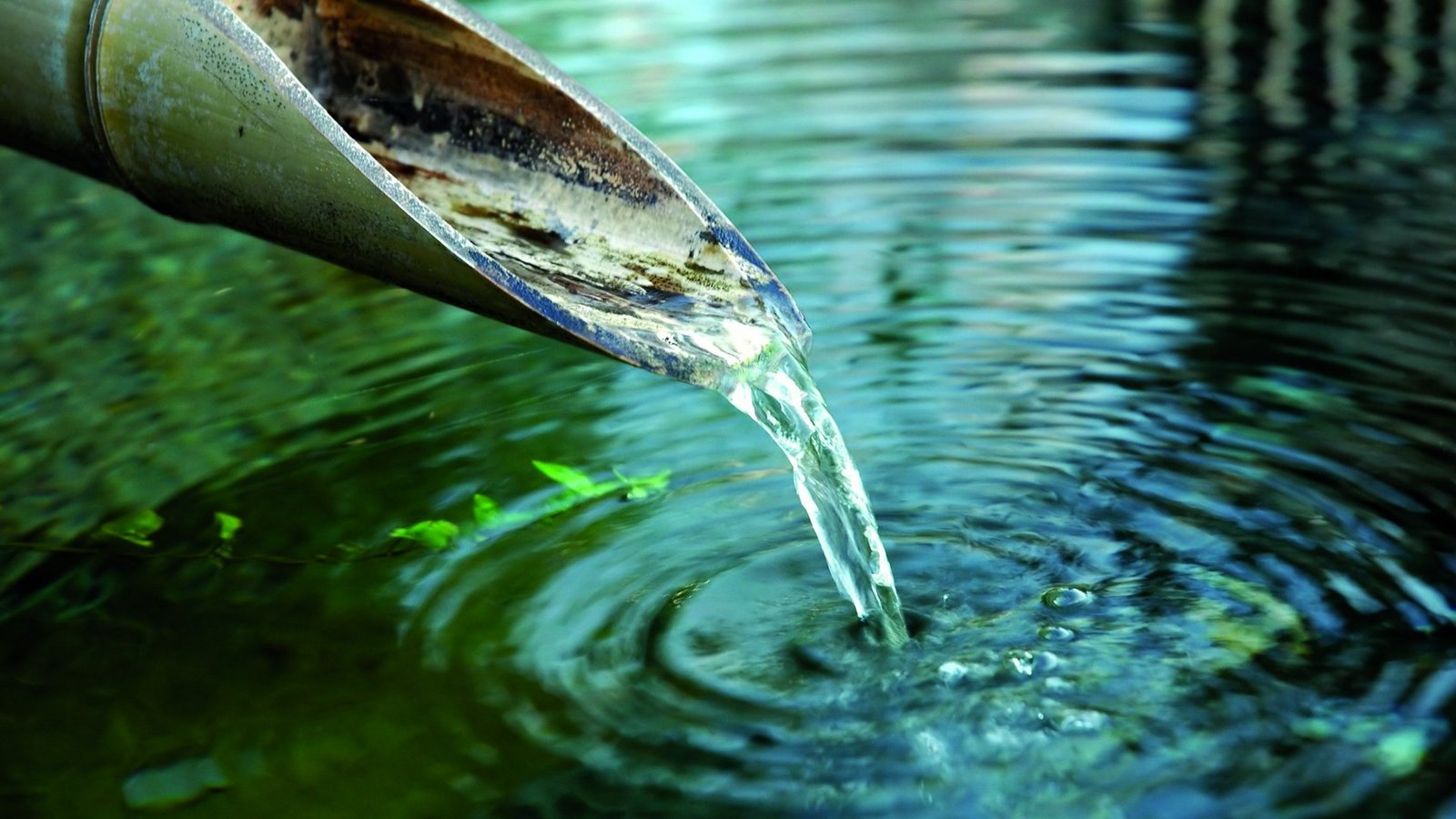 klares Wasser fließt aus einem Bambusrohr in Gewässer