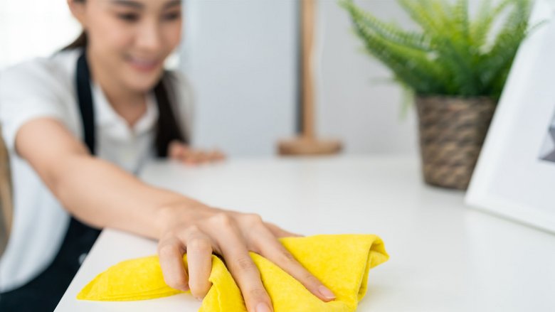 Frau wischt mit gelben Tuch eine Fläche